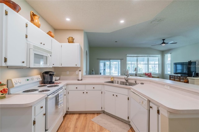 kitchen featuring sink, a healthy amount of sunlight, kitchen peninsula, white appliances, and white cabinets