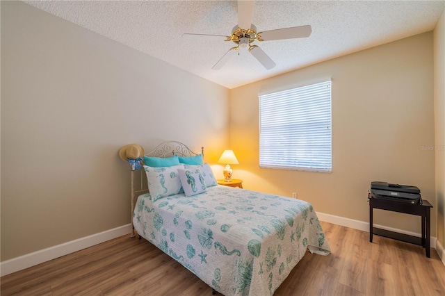 bedroom featuring ceiling fan, a textured ceiling, and light wood-type flooring