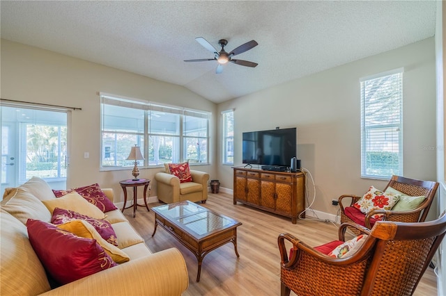 living room featuring ceiling fan, vaulted ceiling, a textured ceiling, and light hardwood / wood-style flooring