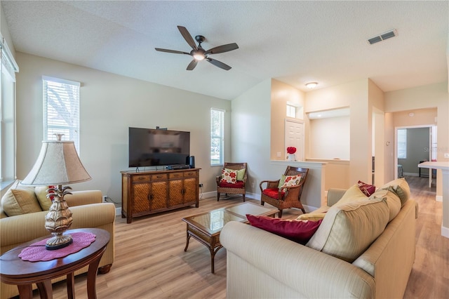 living room with ceiling fan, light hardwood / wood-style flooring, and a textured ceiling