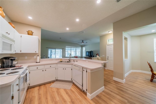 kitchen with kitchen peninsula, white appliances, white cabinets, and sink