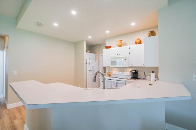 kitchen with white appliances, sink, kitchen peninsula, light hardwood / wood-style floors, and white cabinetry