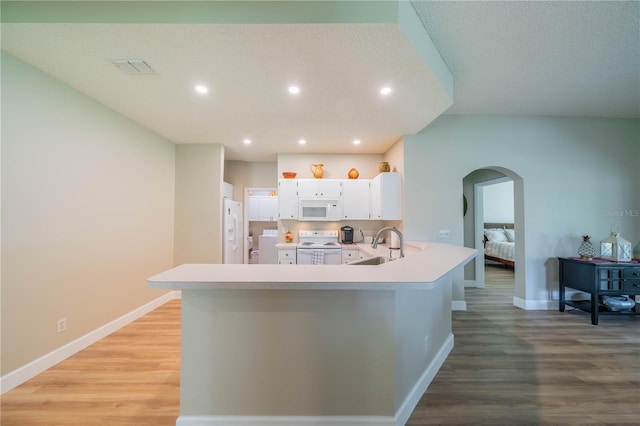 kitchen featuring kitchen peninsula, light wood-type flooring, white appliances, a textured ceiling, and white cabinetry