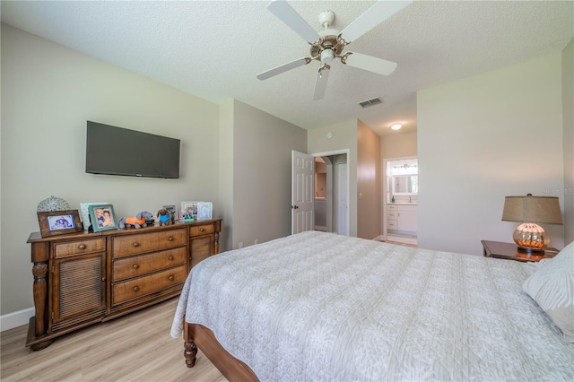 bedroom featuring ensuite bathroom, ceiling fan, a textured ceiling, and light wood-type flooring