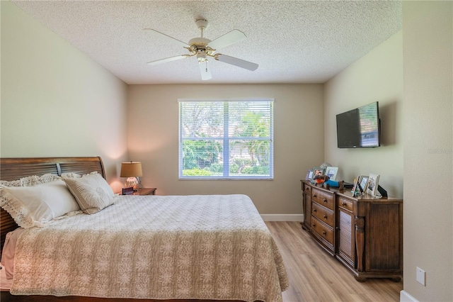 bedroom with a textured ceiling, light hardwood / wood-style floors, and ceiling fan