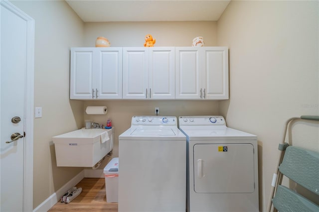 clothes washing area with cabinets, separate washer and dryer, light hardwood / wood-style floors, and sink