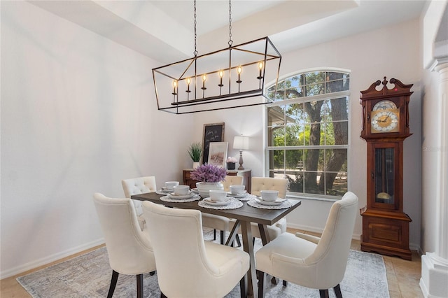 dining room featuring a notable chandelier, a tray ceiling, and light tile flooring