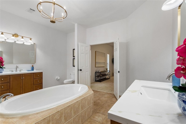 bathroom featuring tile flooring, tiled tub, toilet, and vanity