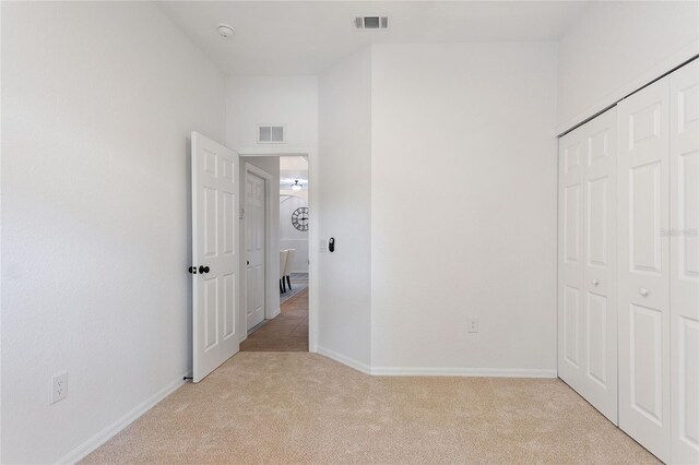 unfurnished bedroom featuring a closet and light colored carpet