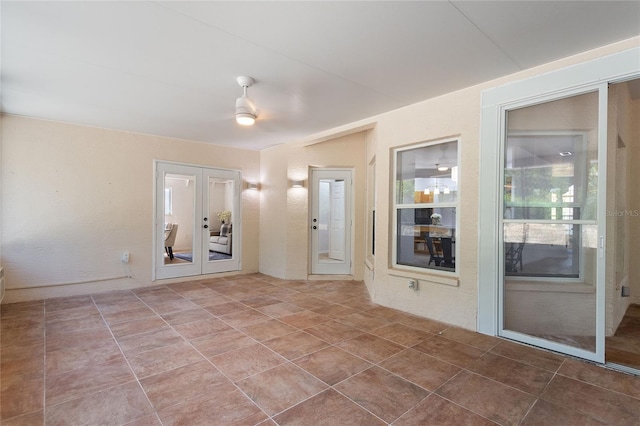 tiled empty room with ceiling fan and french doors