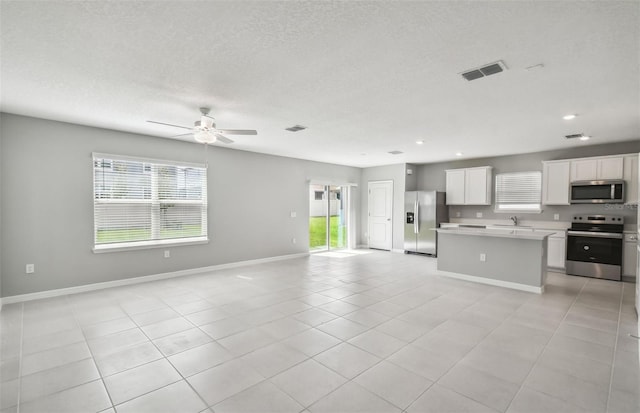 kitchen featuring a healthy amount of sunlight, white cabinetry, stainless steel appliances, and light tile patterned floors