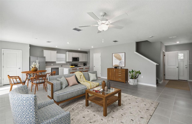 tiled living room with ceiling fan and a textured ceiling