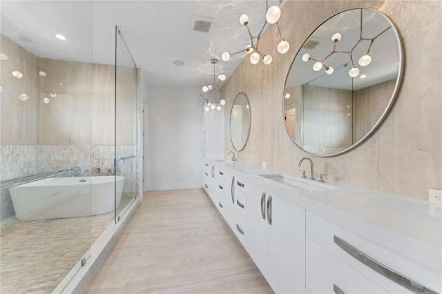 full bathroom with double vanity, visible vents, a freestanding tub, and a sink