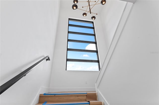 stairs featuring baseboards, an inviting chandelier, and wood finished floors