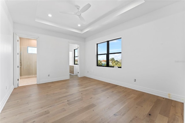 unfurnished room with baseboards, a tray ceiling, recessed lighting, light wood-style flooring, and a ceiling fan