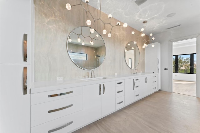 bathroom featuring double vanity, visible vents, wood finished floors, and a sink