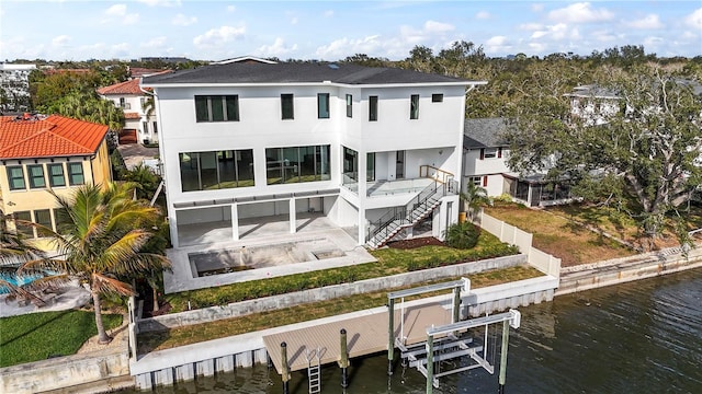 back of property with a water view, stairs, a fenced backyard, a patio area, and boat lift