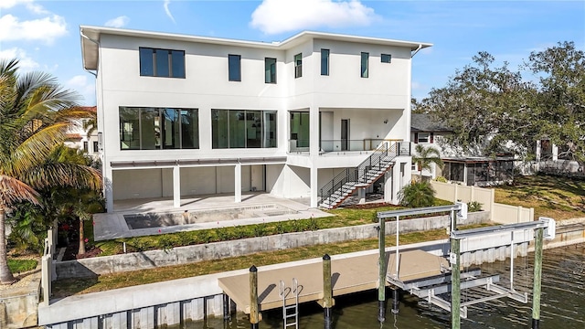 back of house featuring fence, stairway, stucco siding, a patio area, and boat lift