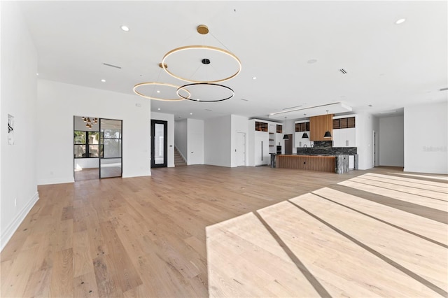 unfurnished living room with recessed lighting, baseboards, and light wood-style floors