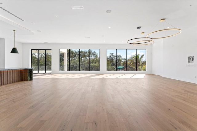 unfurnished living room featuring visible vents, baseboards, light wood finished floors, an inviting chandelier, and recessed lighting