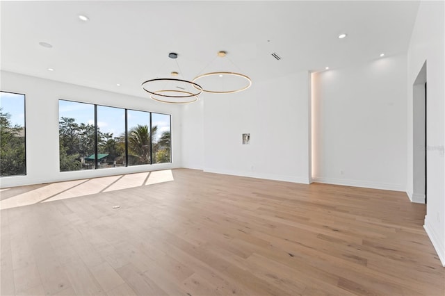 empty room with visible vents, baseboards, a chandelier, recessed lighting, and light wood-style floors