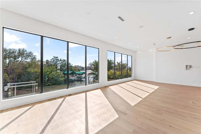 unfurnished room featuring visible vents, baseboards, recessed lighting, light wood-style floors, and a notable chandelier