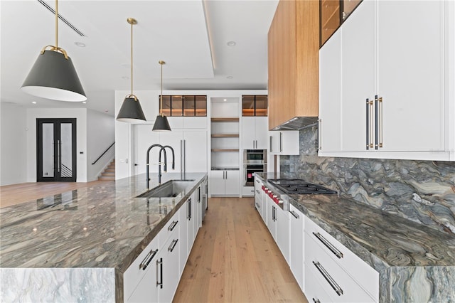 kitchen with a sink, tasteful backsplash, a spacious island, appliances with stainless steel finishes, and light wood finished floors