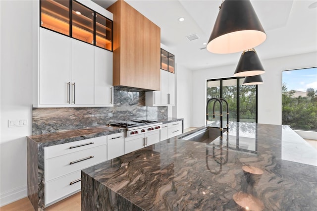 kitchen featuring a sink, backsplash, modern cabinets, and stainless steel gas cooktop