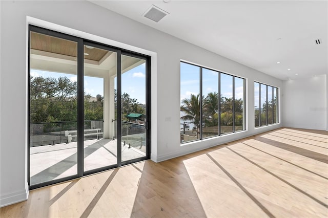 interior space featuring visible vents, a healthy amount of sunlight, baseboards, and wood finished floors