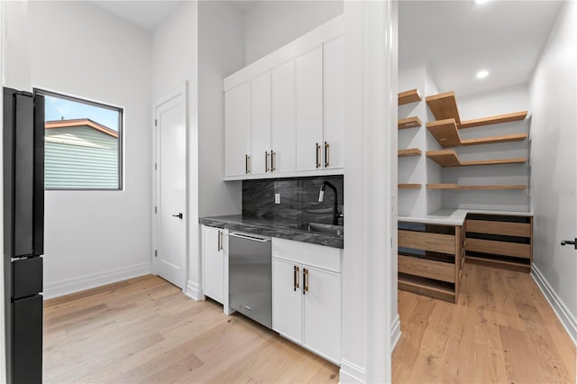 kitchen with dishwasher, freestanding refrigerator, light wood-style floors, white cabinetry, and a sink