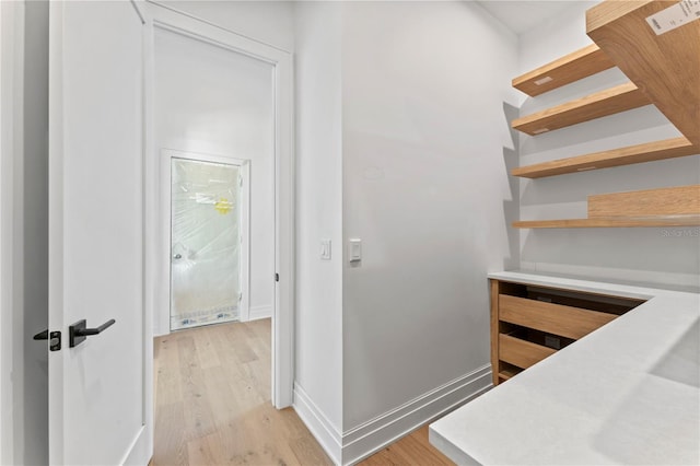 hallway featuring light wood finished floors, visible vents, and baseboards