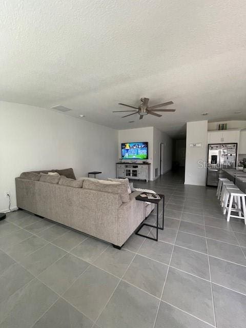 tiled living room with a textured ceiling and ceiling fan