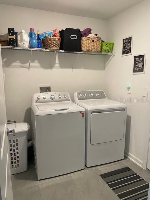 clothes washing area with washer and clothes dryer and light tile patterned floors