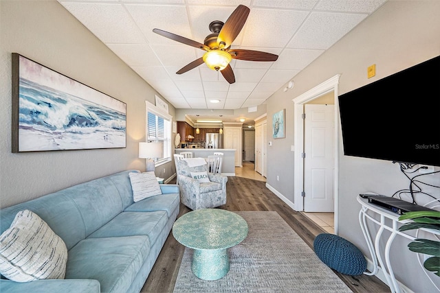 living room featuring ceiling fan, hardwood / wood-style flooring, and a drop ceiling