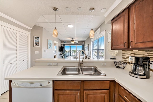 kitchen featuring a sink, light countertops, white dishwasher, and brown cabinetry