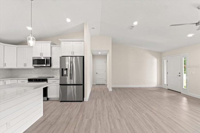 kitchen featuring decorative light fixtures, white cabinetry, stainless steel appliances, decorative backsplash, and vaulted ceiling