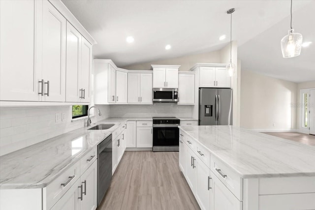 kitchen featuring white cabinetry, stainless steel appliances, decorative backsplash, hanging light fixtures, and vaulted ceiling