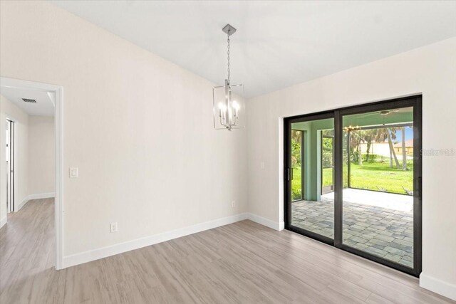 empty room with light hardwood / wood-style flooring and a notable chandelier