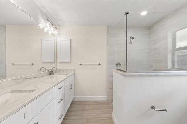 bathroom with tiled shower, hardwood / wood-style flooring, and vanity