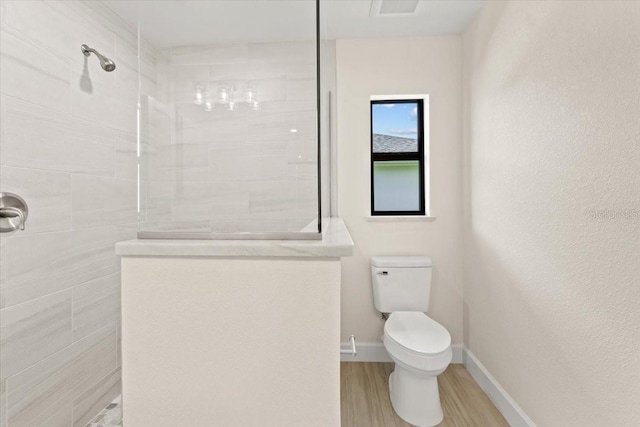 bathroom featuring toilet, hardwood / wood-style floors, and tiled shower