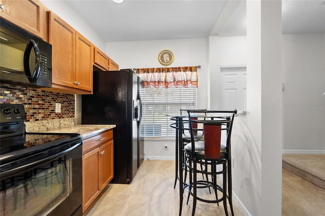 8545 Trail Wind Dr, Tampa, FL 33647 - kitchen with backsplash, light stone countertops, light tile patterned floors, and black appliances