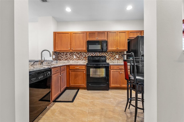 8545 Trail Wind Dr, Tampa, FL 33647 - kitchen with sink, light tile patterned floors, light stone countertops, black appliances, and decorative backsplash