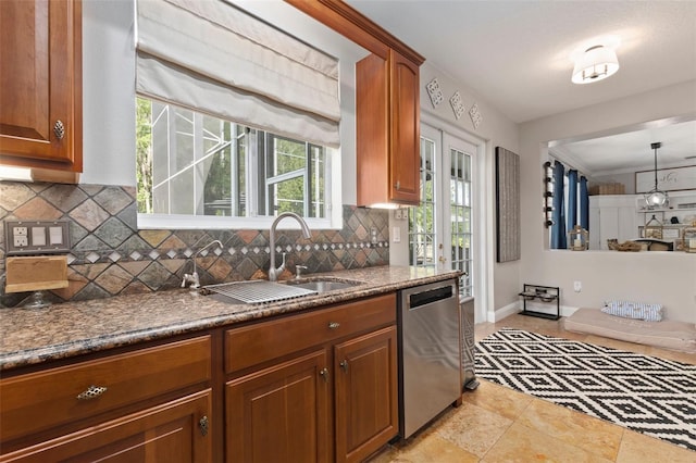 kitchen with stainless steel dishwasher, backsplash, sink, and hanging light fixtures