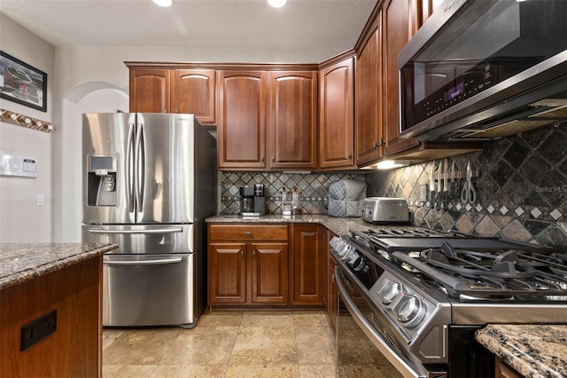 kitchen with stone countertops, appliances with stainless steel finishes, and tasteful backsplash