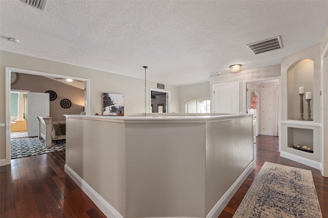 hall featuring a textured ceiling and dark wood-type flooring