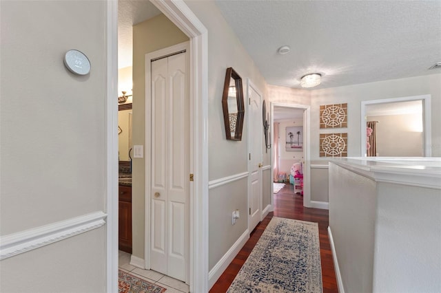 hallway with hardwood / wood-style floors and a textured ceiling