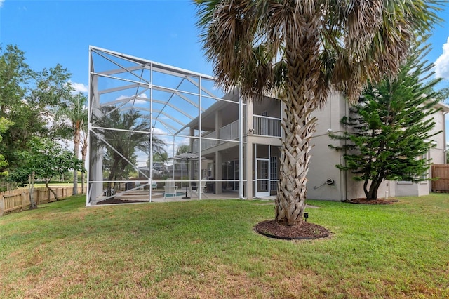 rear view of property featuring a yard, glass enclosure, and a swimming pool