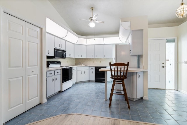 kitchen with ceiling fan, sink, a breakfast bar area, white cabinets, and black appliances