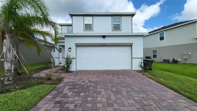 traditional home with an attached garage, stucco siding, a front lawn, central air condition unit, and decorative driveway