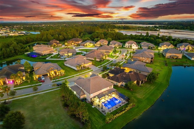 aerial view at dusk featuring a water view